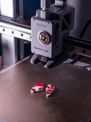 Close-up of a 3D printer creating red and white plastic objects.