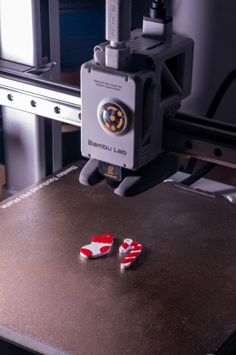 Close-up of a 3D printer creating red and white plastic objects.